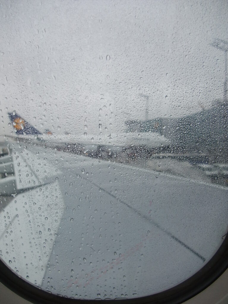 Blick aus dem Flugzeug auf den Flugzeugflügel bei grauem Nieselwetter